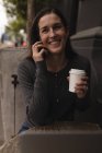 Femme heureuse parlant sur téléphone mobile dans un café extérieur — Photo de stock