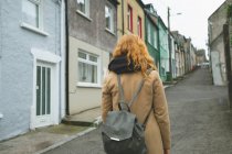 Vista trasera de la mujer pelirroja de pie en la calle callejón - foto de stock