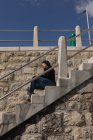 Вид збоку жінки з обмеженими можливостями, що використовує мобільний телефон на сходах — стокове фото