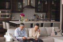 Senior couple using digital tablet and talking on mobile phone at home — Stock Photo