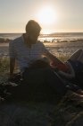 Giovane donna sdraiata sulle ginocchia mans in spiaggia — Foto stock