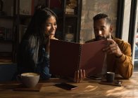 Glückliches Paar schaut sich Speisekarte im Café an — Stockfoto