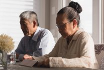 Seniorin nutzt digitales Tablet zu Hause auf Esstisch — Stockfoto