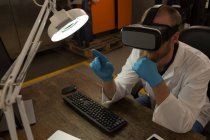 Robotics engineer using virtual reality headset at desk in warehouse — Stock Photo