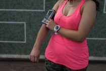 Partie médiane de joggeuse utilisant un téléphone portable — Photo de stock
