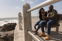 Счастливая пара обсуждают на мобильном телефоне на набережной — стоковое фото