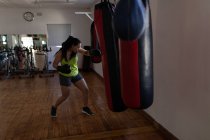 Jeune boxeuse pratiquant la boxe dans un studio de fitness — Photo de stock