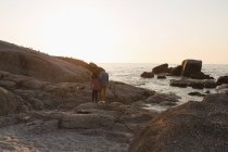 Vista posteriore della coppia che cammina sulla roccia vicino al mare — Foto stock