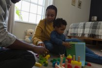 Familia jugando con un niño en una sala de estar en casa - foto de stock