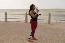 Seitenansicht einer behinderten Frau, die Wasser auf der Promenade trinkt — Stockfoto