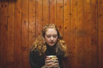 Donna rossa che tiene una tazza di caffè nel caffè — Foto stock