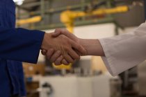 Close-up of robotic engineers shaking hands with each other — Stock Photo