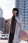 Hijab femmes prendre un café froid tout en parlant sur un téléphone mobile en ville — Photo de stock