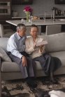 Старша пара обговорює цифровий планшет на дивані у вітальні вдома — стокове фото