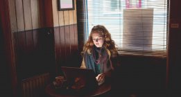 Redhead woman using laptop in cafe — Stock Photo