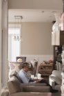 Homme âgé utilisant une tablette numérique dans le salon à la maison — Photo de stock