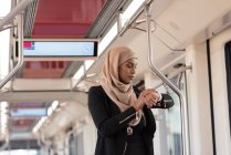 Хиджаб женщина с помощью умных часов во время путешествия на поезде — стоковое фото