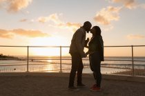 Romántica pareja besándose en el paseo marítimo - foto de stock