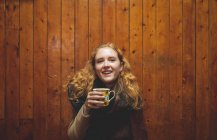 Рыжая женщина держит кофейную кружку в кафе — стоковое фото