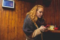 Donna rossa che utilizza il telefono cellulare in caffè — Foto stock