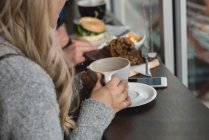 Primer plano de la mujer tomando café en la cafetería - foto de stock