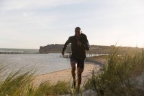 Чоловік спортсмен біжить біля пляжу в сонячний день — стокове фото