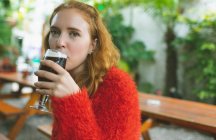 Рыжая женщина пьет пиво в кафе на открытом воздухе — стоковое фото