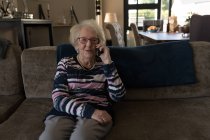 Seniorin telefoniert zu Hause im Wohnzimmer — Stockfoto
