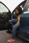 Vue latérale de la femme handicapée attachant lacet de chaussure tout en étant assis dans la voiture — Photo de stock