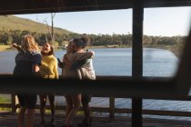 Friends hugging each other in cabin near lake — Stock Photo