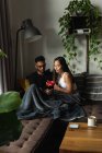 Couple utilisant un téléphone portable tout en prenant un café dans le salon à la maison — Photo de stock