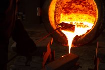 Рабочие заливают расплавленный металл из колб в литейные формы в литейном цехе — стоковое фото