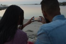 Vista trasera de la pareja tomando fotos en el teléfono móvil - foto de stock