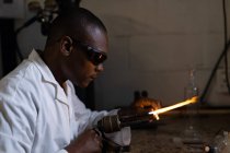 Вид сбоку работника с помощью сварочной горелки на стекольном заводе — стоковое фото