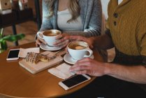 Sección media de la pareja tomando café en la cafetería - foto de stock