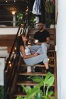 Couple interagissant les uns avec les autres tout en prenant un café dans les escaliers à la maison — Photo de stock
