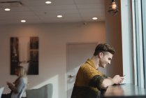 Вид збоку людини, що використовує мобільний телефон у кафе — стокове фото
