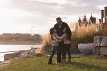 Großvater und Enkelinnen umarmen sich am Seeufer — Stockfoto