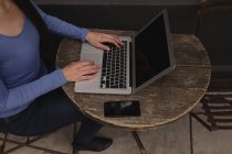 Низька частина жінки, що використовує ноутбук у відкритому кафе — стокове фото