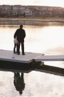 Вид сзади на дедушку и внучку, стоящих на пирсе возле озера — стоковое фото