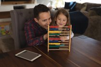 Father playing abacus with his daughter in living room at home — Stock Photo