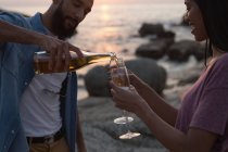 Romantic couple having champagne near sea side — Stock Photo