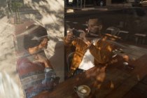 Умный мужчина фотографирует женщину в кафе — стоковое фото