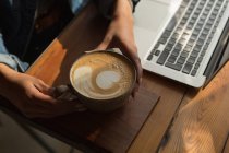 Крупный план женщины, держащей чашку кофе в кафе — стоковое фото
