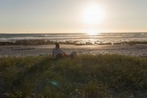 Женщина, лежащая на ноге мужчины на пляже во время заката — стоковое фото