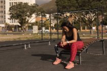 Nachdenkliche behinderte Frau sitzt auf der Trainingsbank — Stockfoto