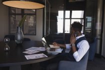Geschäftsmann schreibt Tagebuch, während er mit dem Handy im Konferenzraum im Büro spricht — Stockfoto