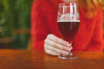 Средняя секция женщины, держащей стакан пива в открытом кафе — стоковое фото