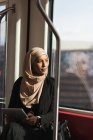 Hijab woman looking through window while using digital tablet in train — Stock Photo