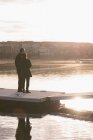 Вид сзади на пожилую пару, стоящую на пирсе возле озера — стоковое фото